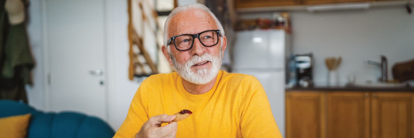 Elderly man in kitchen eating