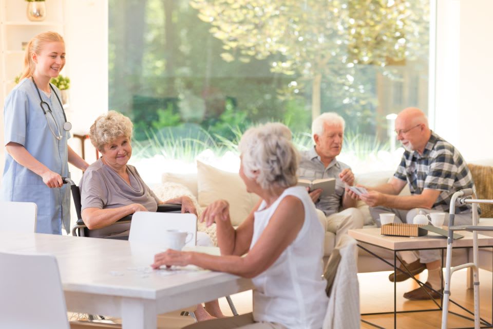 A group of elderly people chatting at two tables