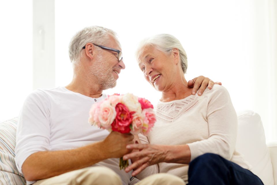 Elderly woman receives flowers from partner.